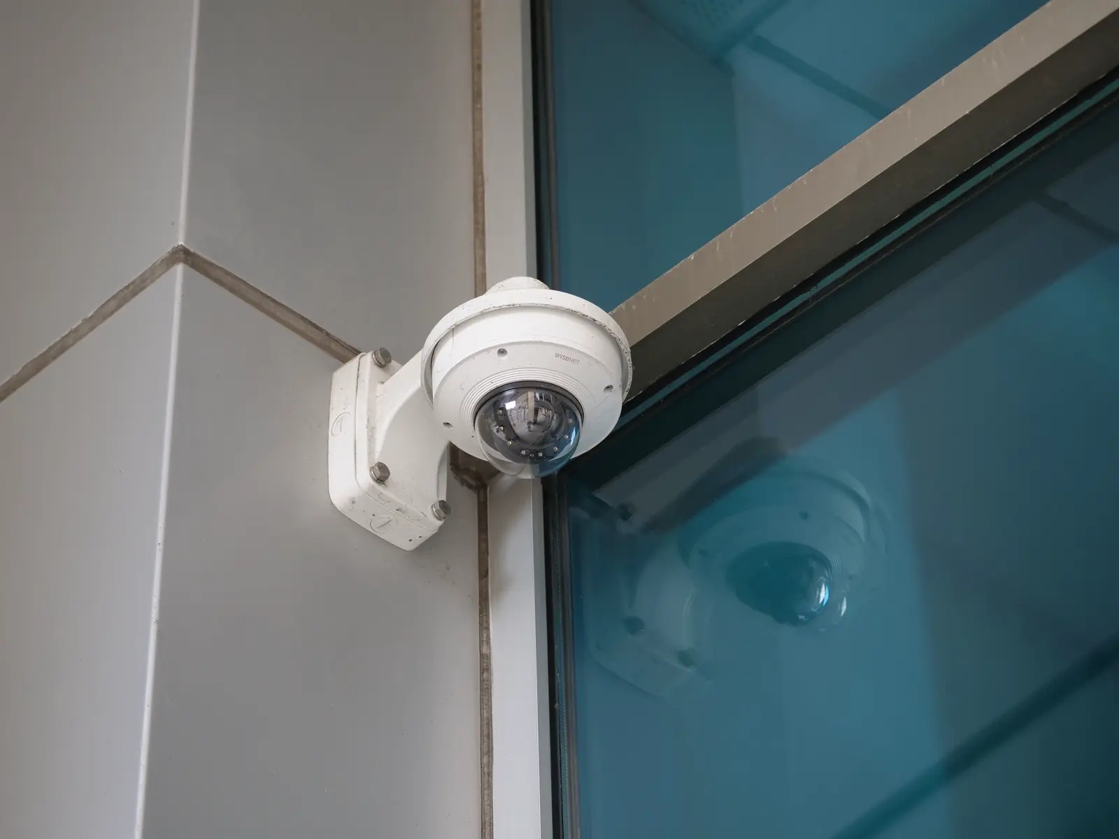 An unbranded dome camera mounted on a modern glass building.
