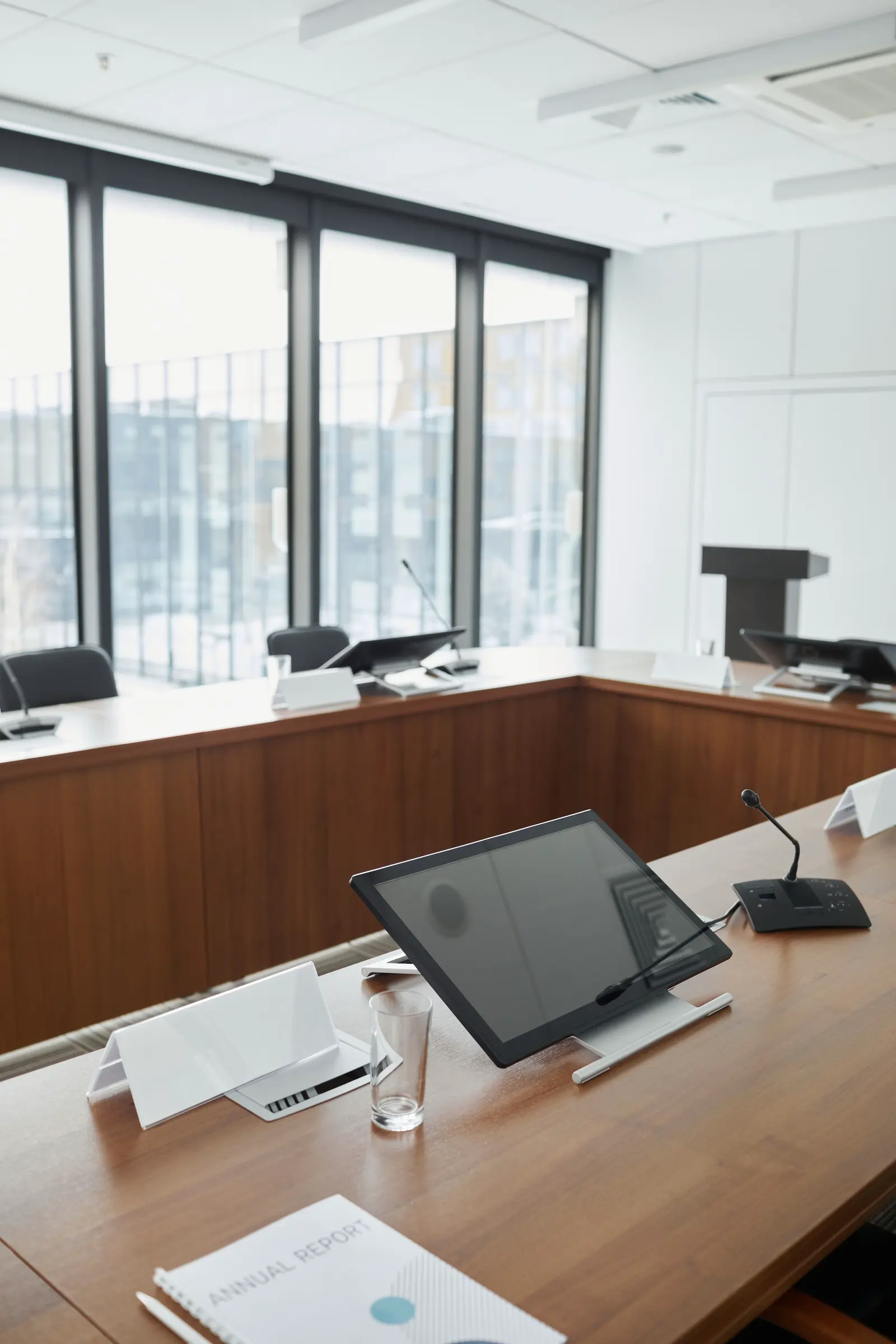 A modern conference room with displays and desk microphones at each seat.