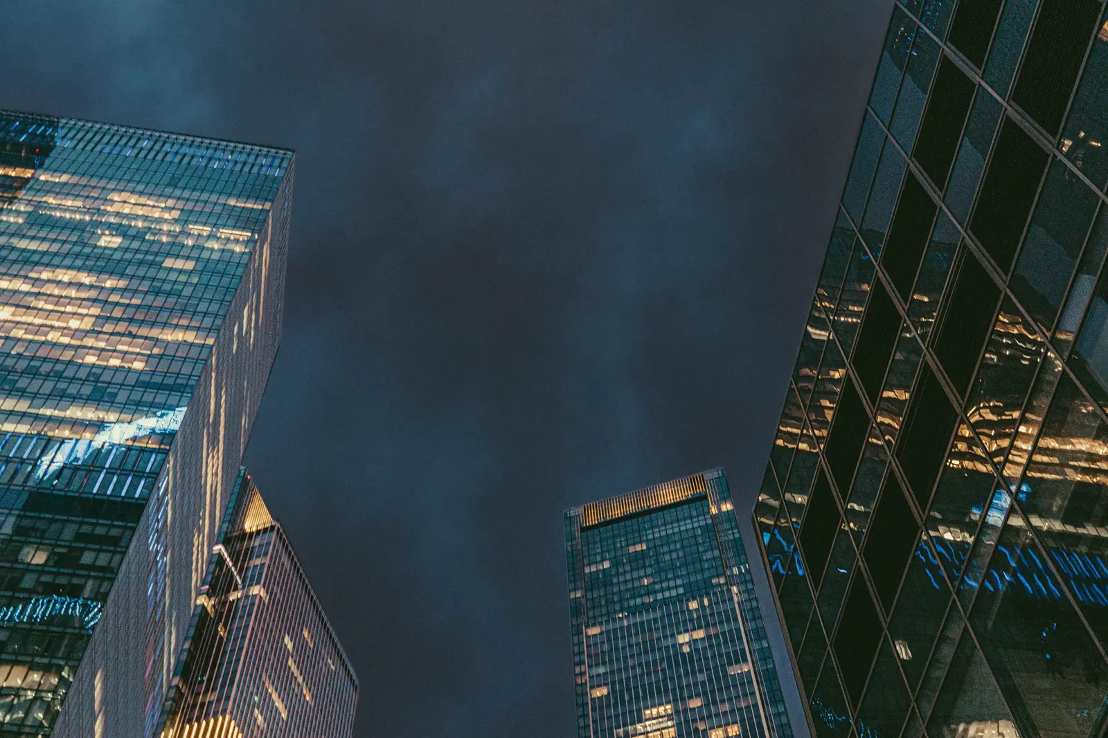 Illuminated office towers seen from street level at dusk.