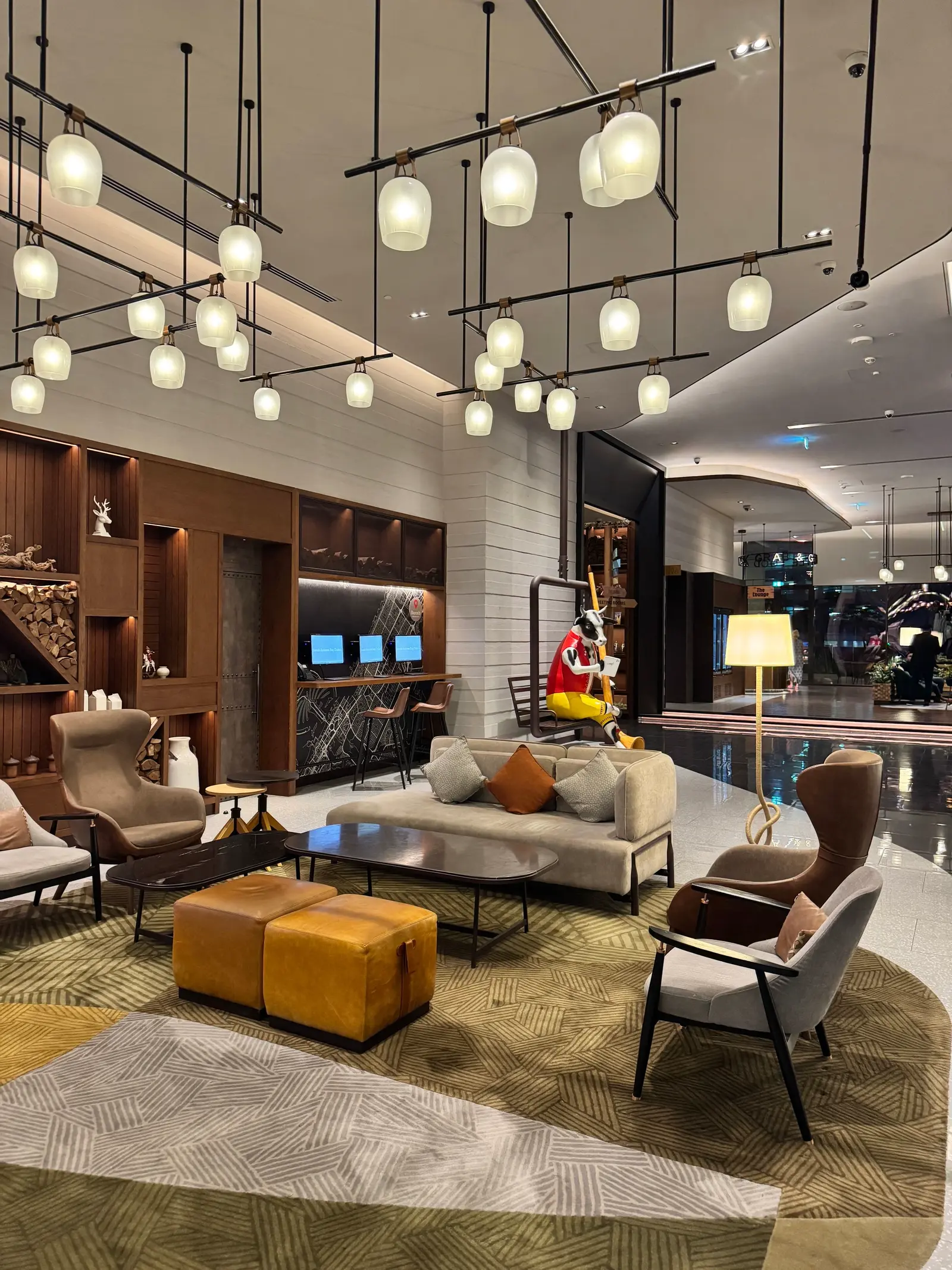 A modern hotel lobby with pendant lighting and seating groups.