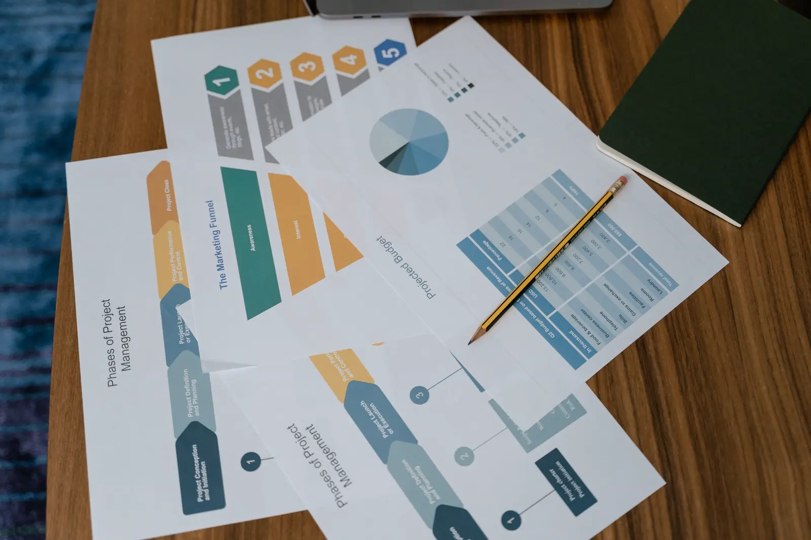 Printed project-phase charts and schedules spread across a working table.
