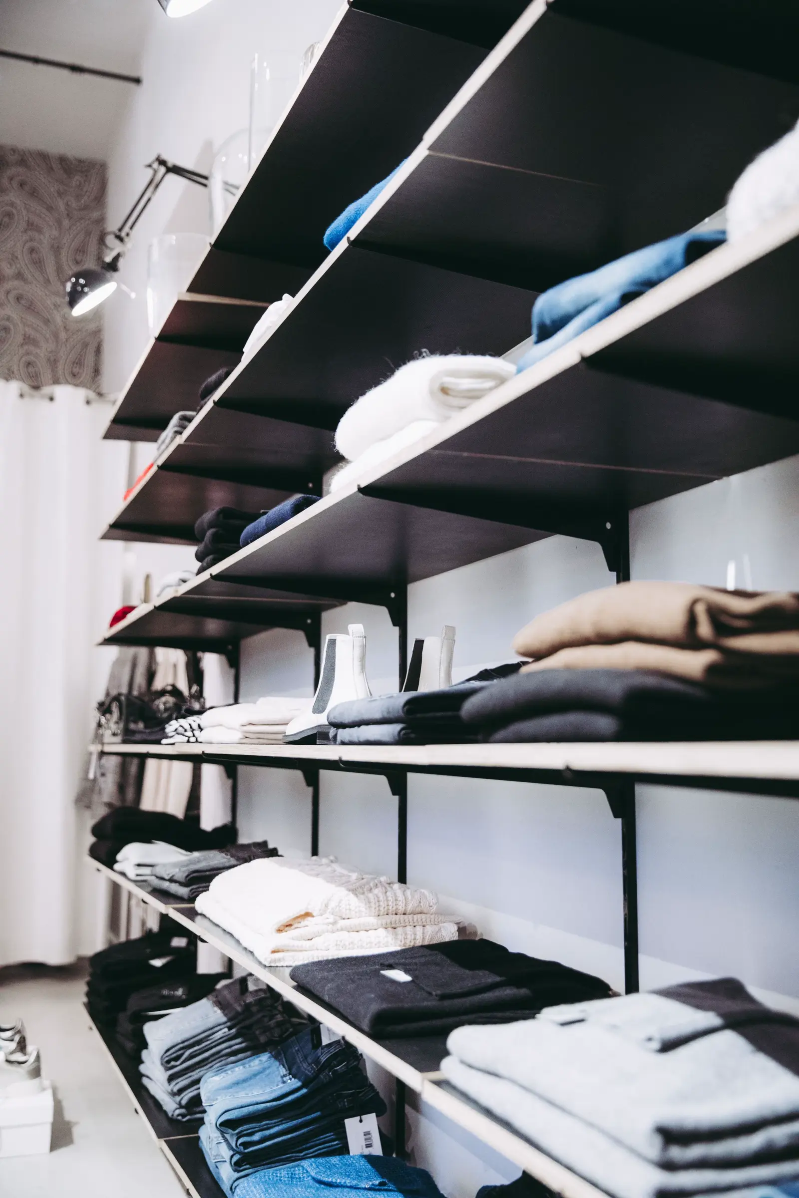 Folded apparel arranged on clean retail shelving.