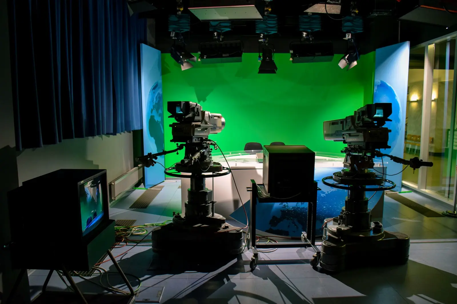 Studio pedestal cameras in front of a green-screen news set.