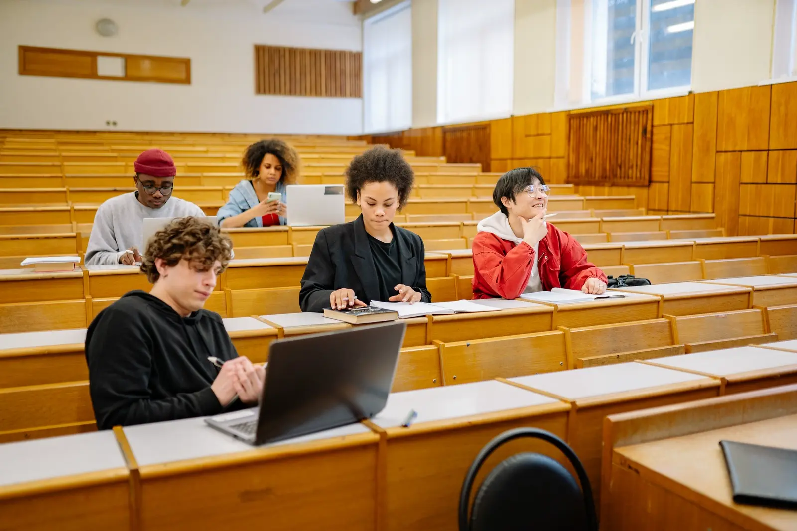 Learners with laptops and notes in a tiered training hall.