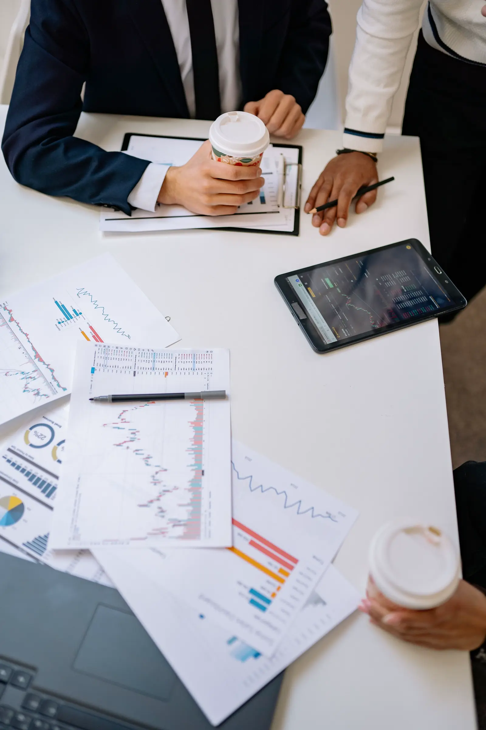 Hands, charts and a tablet over a working table mid-engagement.